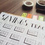 Close-up of a handmade savings tracker with colored tabs on a wooden table, ideal for financial planning visuals.