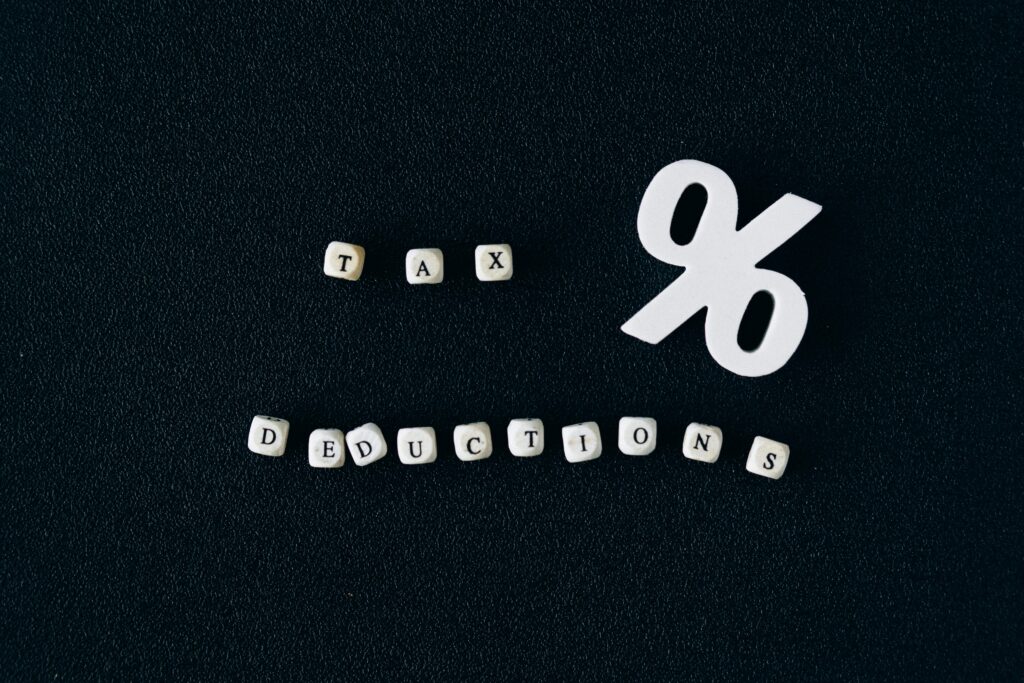 Conceptual image of tax deductions with alphabet blocks and percent symbol on black surface.