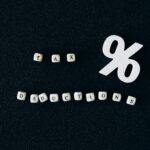 Conceptual image of tax deductions with alphabet blocks and percent symbol on black surface.