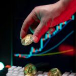 A hand holding cryptocurrency coins with a financial chart in the background, depicting market trends.