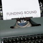 A vintage typewriter displaying the text 'Funding Round,' symbolizing investment and business planning.