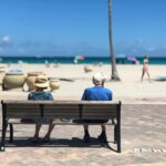 Senior couple sitting on a bench enjoying a sunny day at Hollywood Beach, Florida.